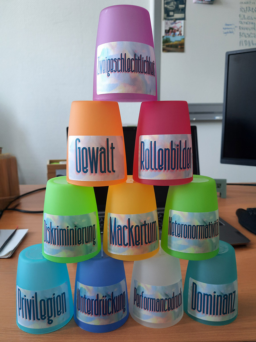 Gestapelte, bunte Becher mit verschiedenen Text-Etiketten versehen, animieren zum Einsturz des Patriarchats