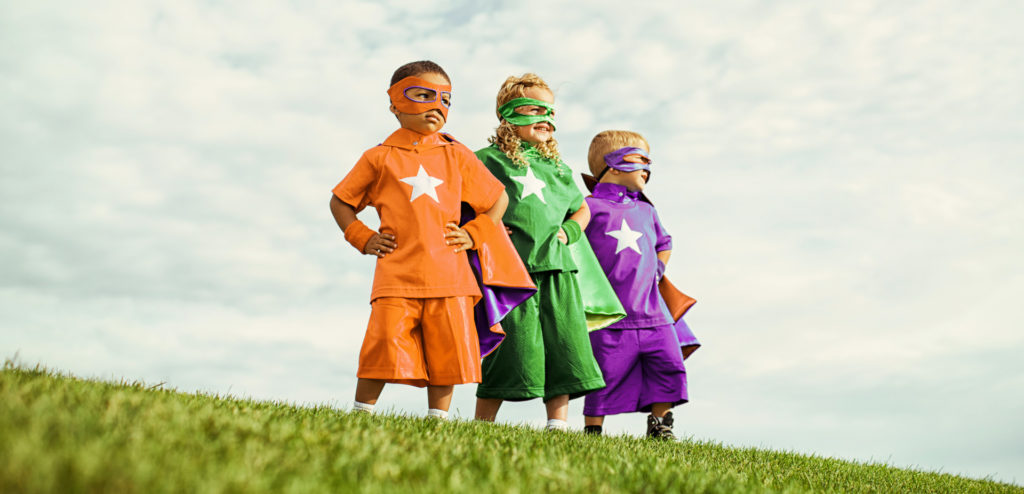 Projekt "Soziale Junge" Headerbild: drei kleine Jungen in farbigen Superheldenkostüm und Masken stehen auf einem Hügel